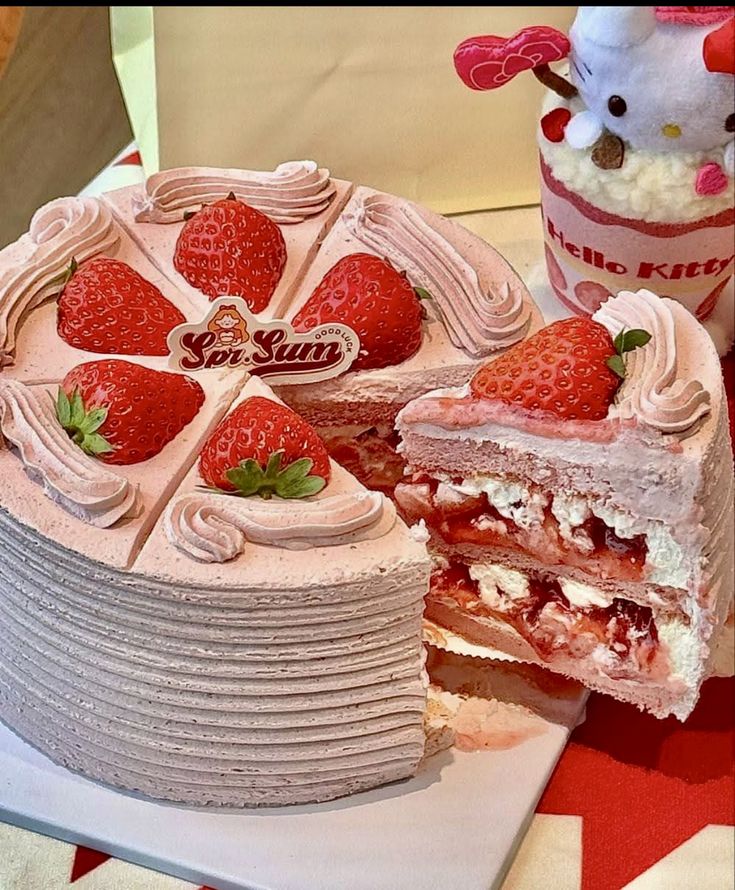liced strawberry cream cake with fresh berries and pink frosting, branded Soi Sun, next to Hello Kitty themed cup.