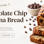 Freshly baked chocolate chip banana bread loaf sliced on a wooden surface, showing a soft, moist texture filled with melted chocolate chips.
