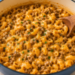 Creamy homemade hamburger helper pasta with ground beef and melted cheddar cheese in a blue pot